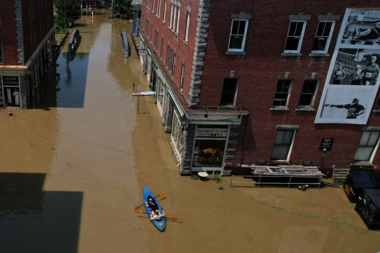 eople paddle a kayak down a street flooded by recent rainstorms in Montpelier, Vermont, July 11.